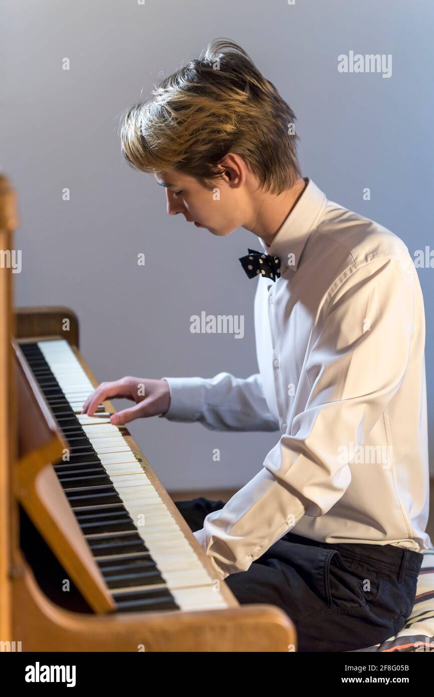 chemise blanche garçon avec noeud papillon joue du piano à la maison Banque D'Images
