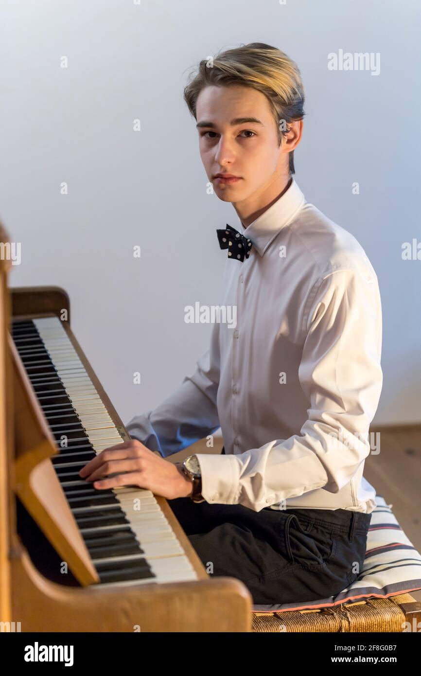 chemise blanche garçon avec noeud papillon joue du piano à la maison Banque D'Images
