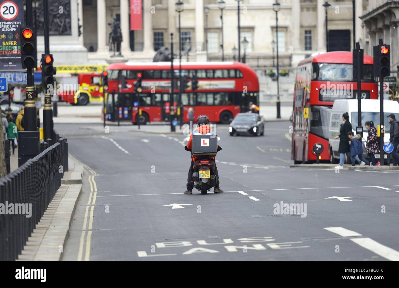 Londres, Angleterre, Royaume-Uni. Conducteur de livraison de moto apprenant à Whitehall, en direction de Trafalgar Square Banque D'Images