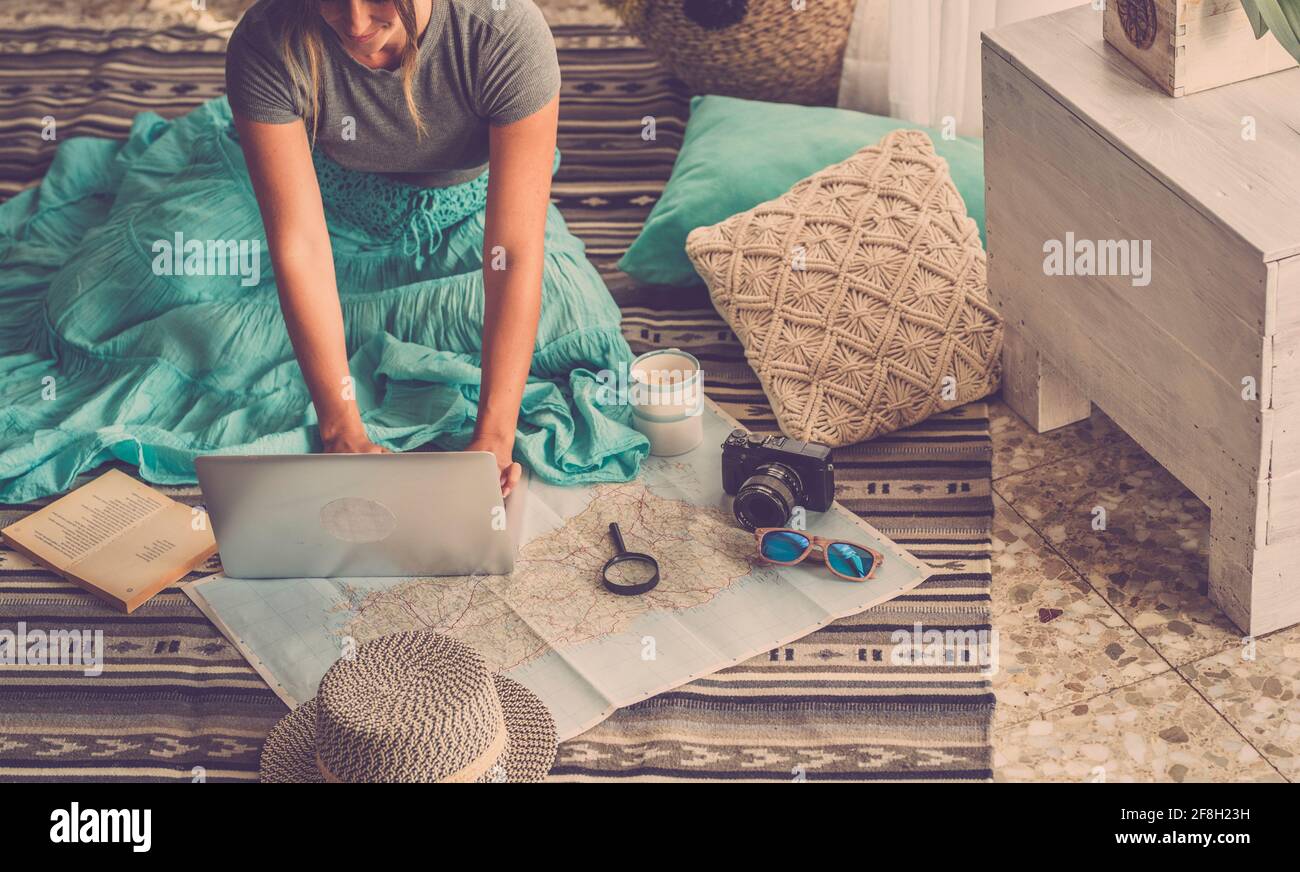 Femme caucasienne planifiant un voyage de vacances avec ordinateur portable et guide de carte à la maison, les femmes planifient les prochaines vacances tout en se relaxant sur l'étage - pr Banque D'Images