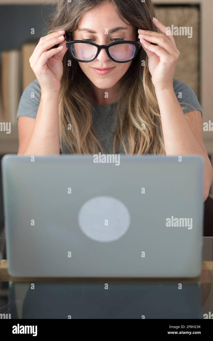 Jolie femme avec des lunettes de travail de lunettes à la maison sur ordinateur portable ordinateur - femmes travaillant intelligemment au bureau regardant le moniteur - mode professionnel Banque D'Images