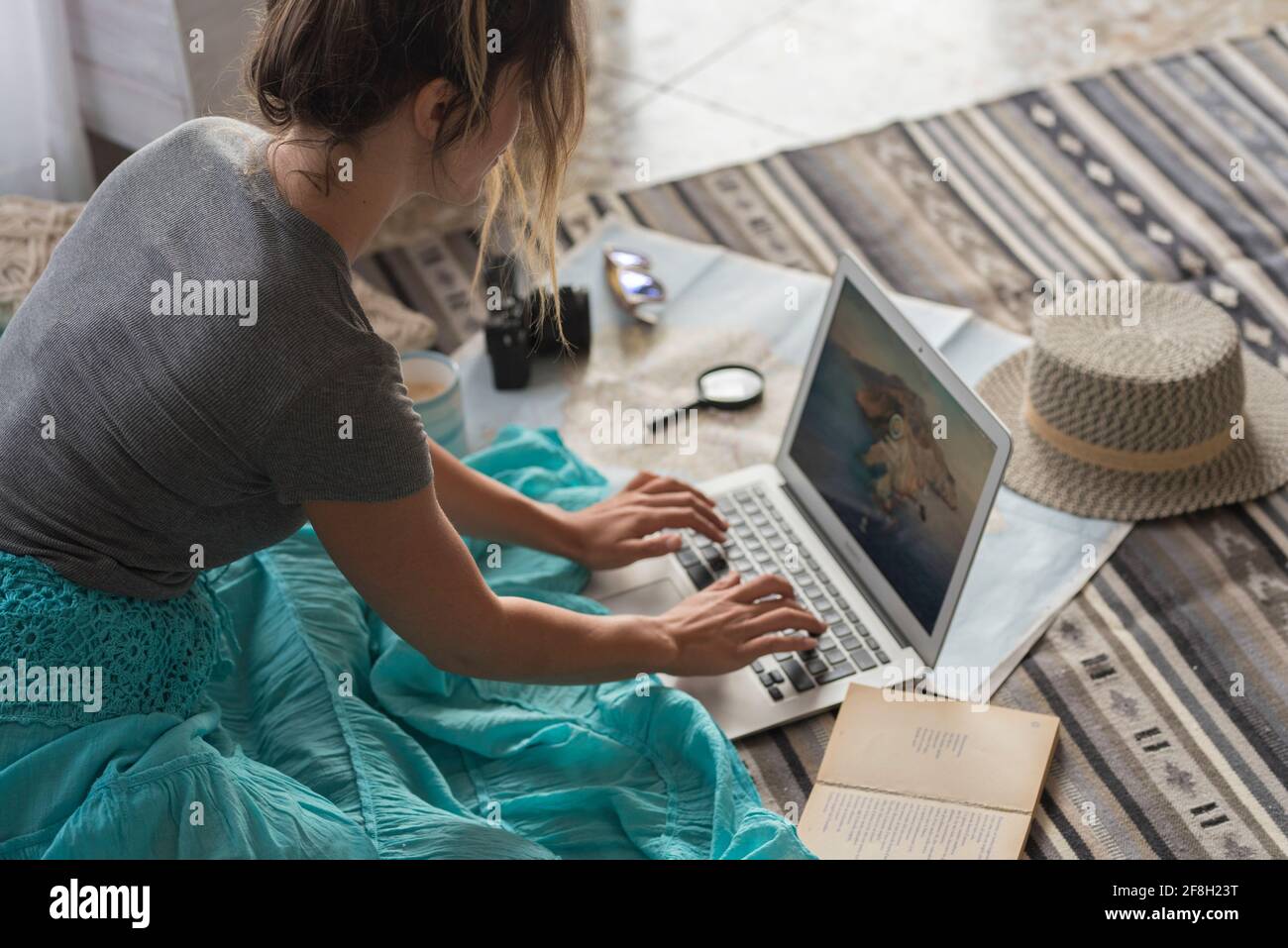 Femme caucasienne planifiant des voyages de vacances avec ordinateur portable et Internet à la maison, lisant le blog touristique en ligne dans Internet tout en se relaxant sur le sol Banque D'Images