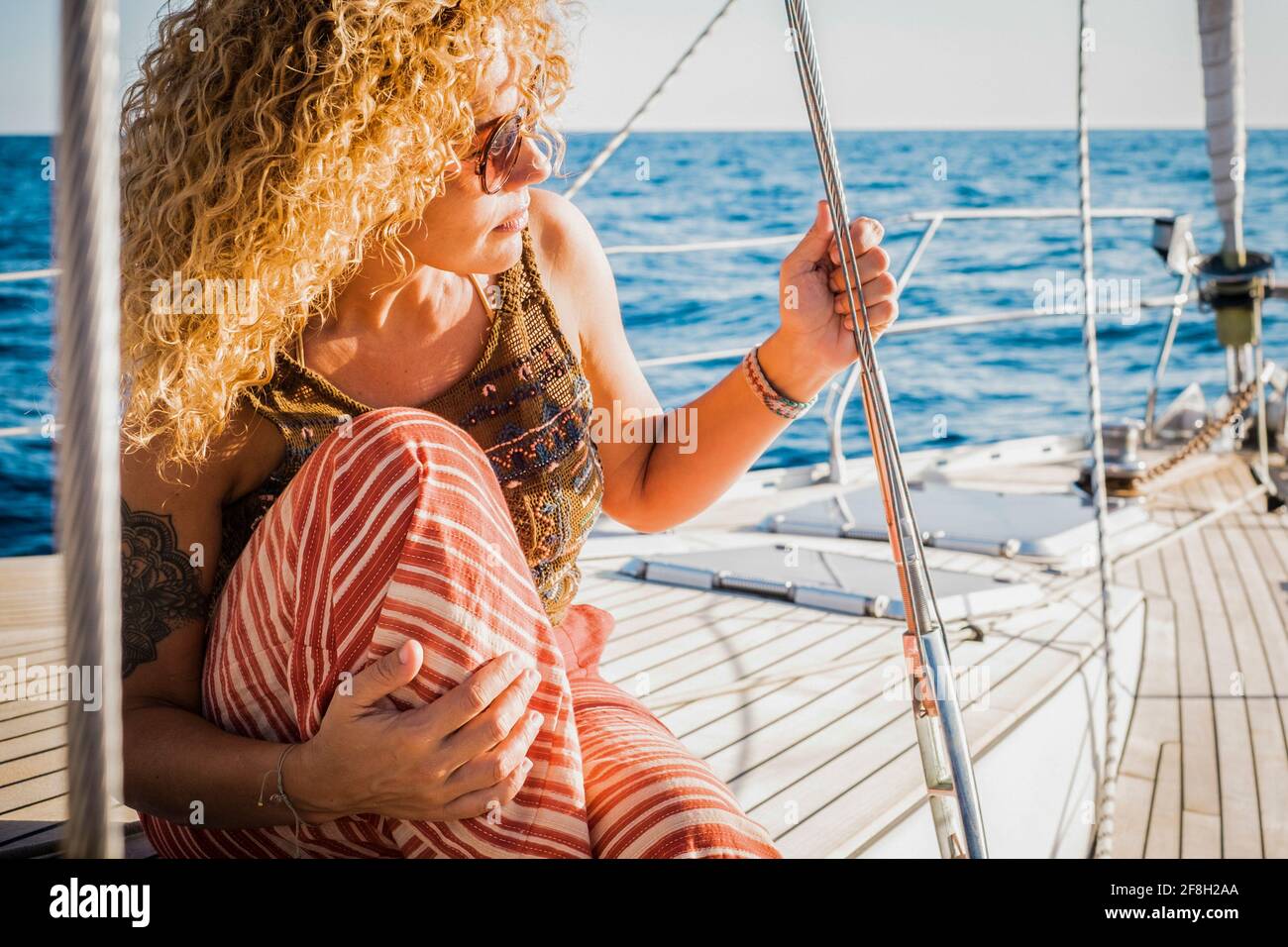 Portrait d'une femme d'âge moyen attrayante assise sur le bois terrasse du yacth appréciant le voyage - concept de style de vie de luxe avec yacht - femme p Banque D'Images