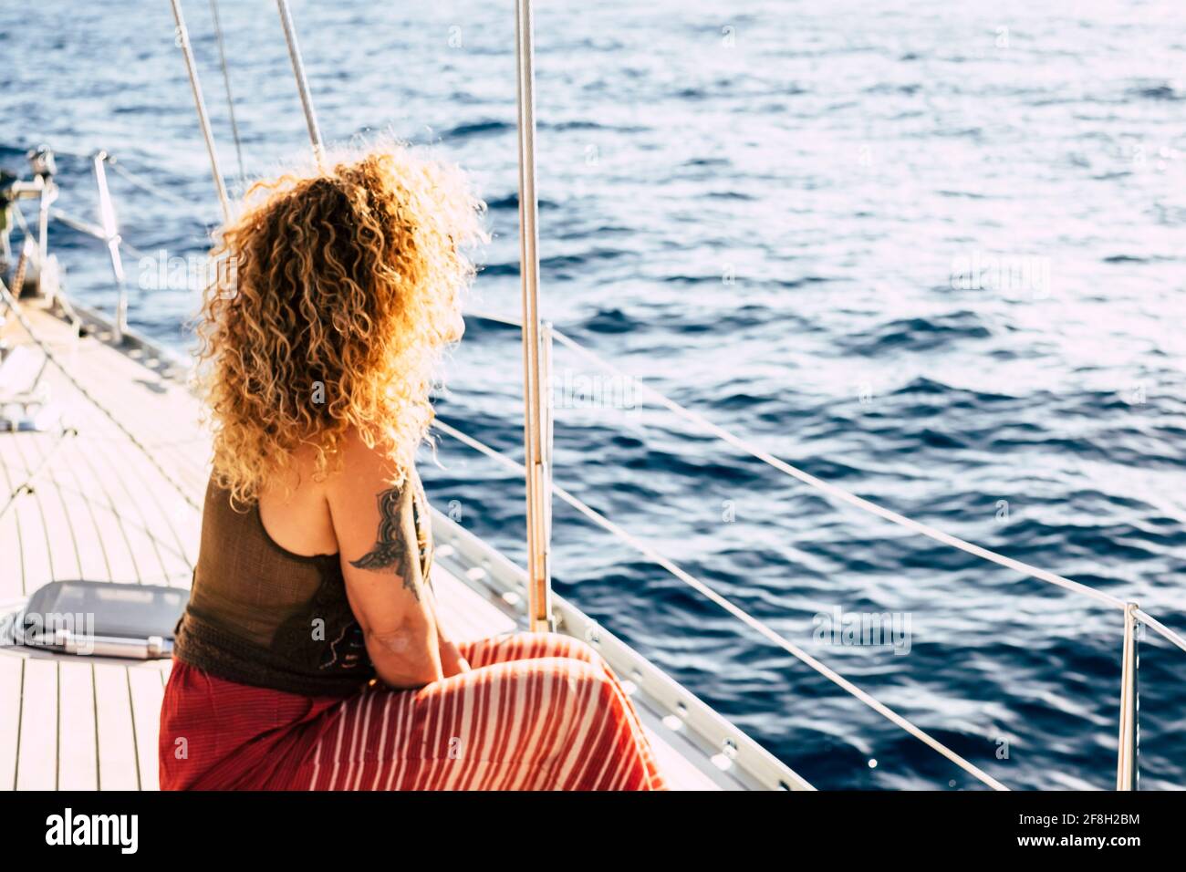 Vue arrière de la femme blonde de cheveux longs et bouclés avec tatoo profiter du voyage sur un bateau - concept de style de vie en vacances d'été pour les touristes Banque D'Images