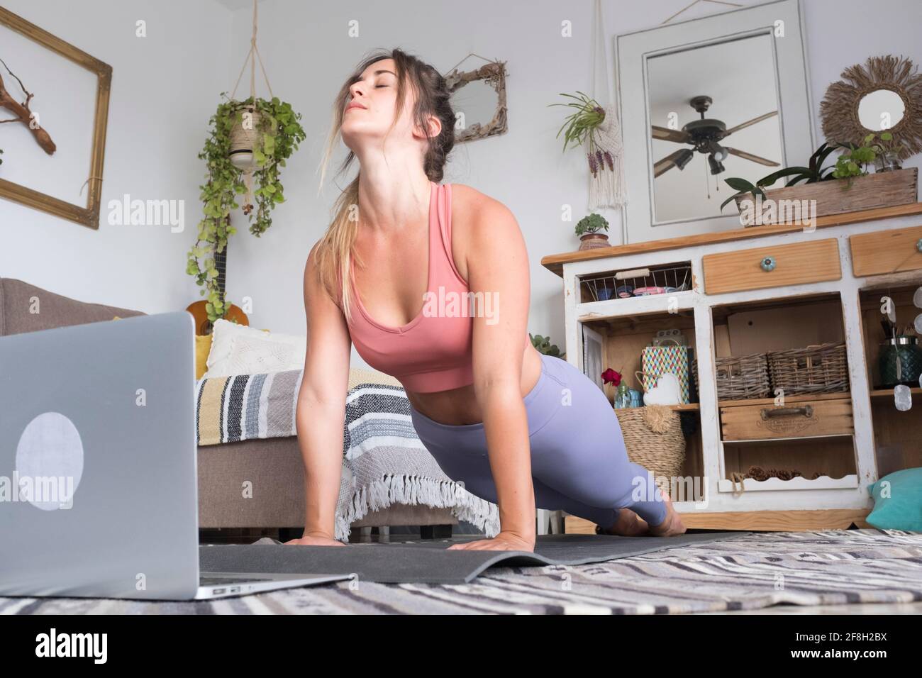 Jeune femme s'exerçant à la maison faisant des push-up et regardant sur son ordinateur portable personnel pour apprendre ou enseigner l'entraînement - le créateur de contenu d'affaires libre il Banque D'Images