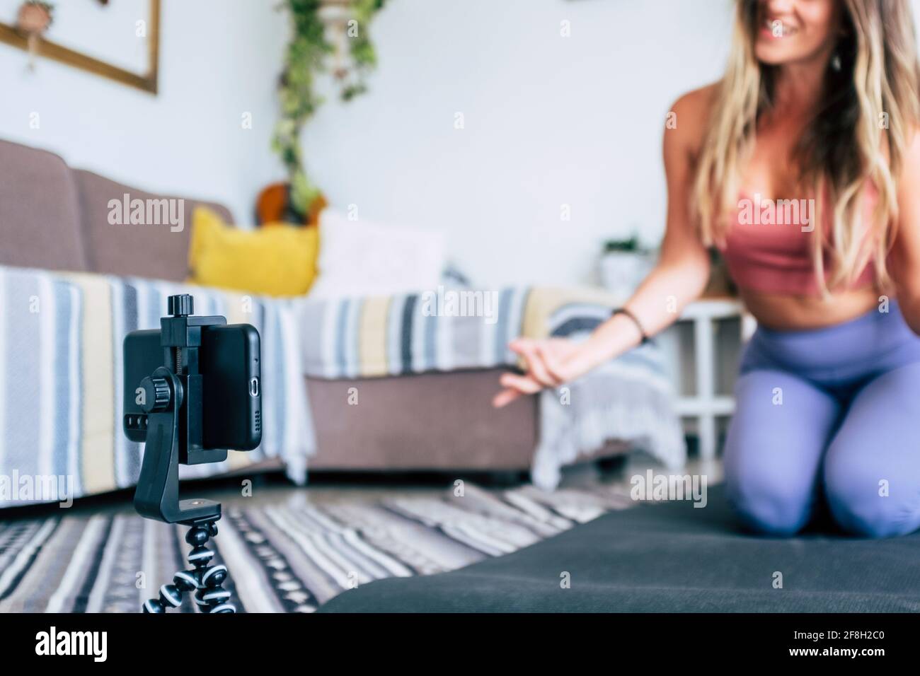 Jeune femme s'exerçant à la maison faisant de l'entraînement et l'enregistrement à elle avec un téléphone cellulaire pour enseigner l'entraînement et produire le web classe - les affaires du créateur de contenu Banque D'Images