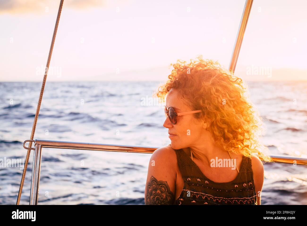 Belle femme profiter du coucher de soleil assis sur le yacht à l'intérieur voyage en mer - portrait des femmes heureux extérieur avec coucher de soleil et océan Banque D'Images