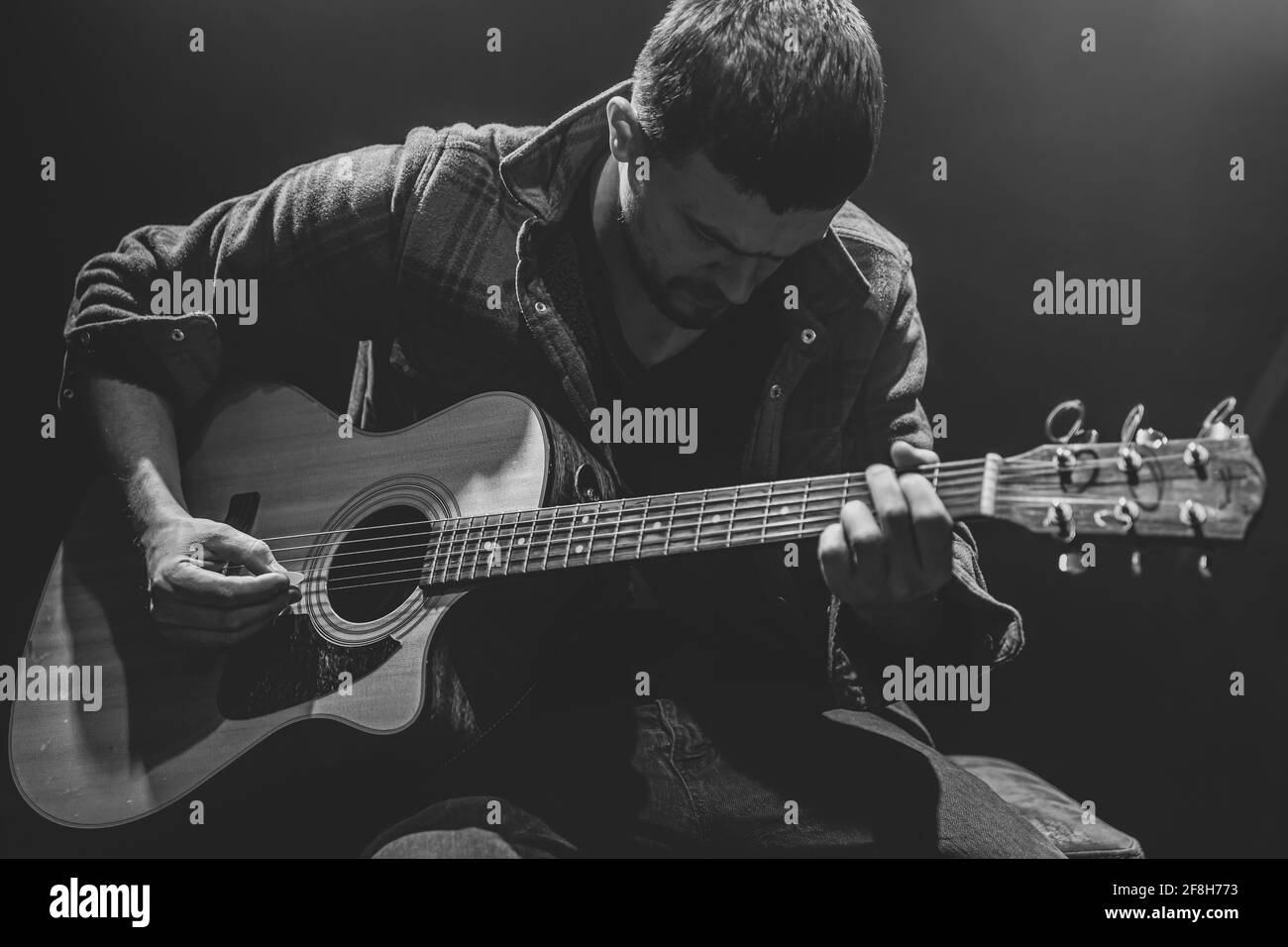 Le musicien joue de la guitare dans une pièce sombre. Banque D'Images
