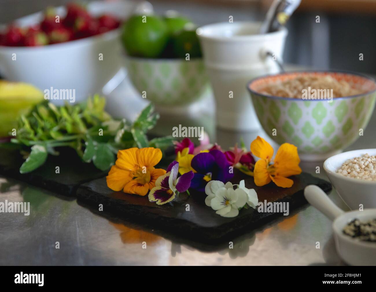 ardoise avec des fleurs fraîches comestibles et des ingrédients dans un bol Banque D'Images