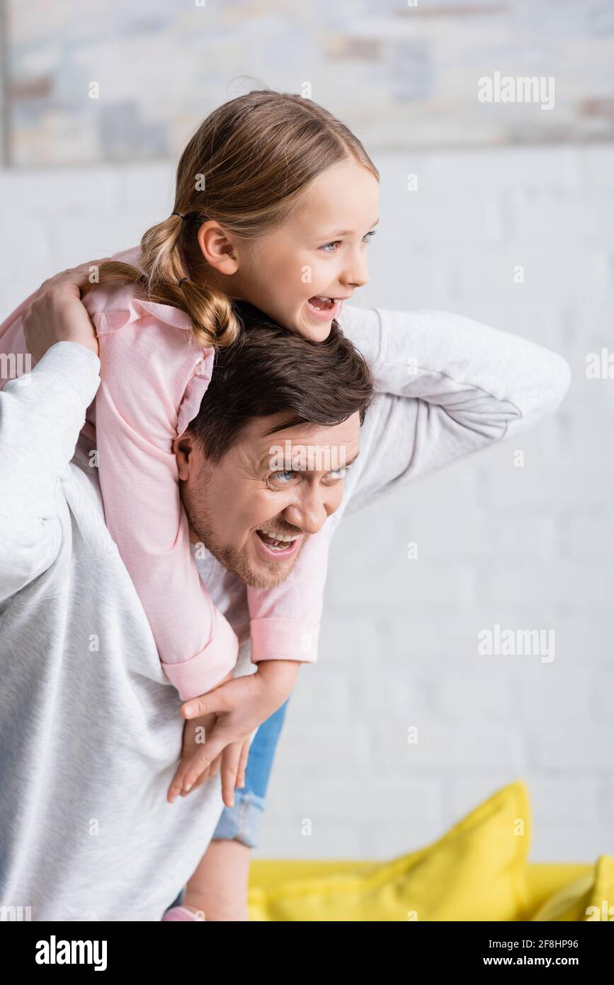 homme joyeux qui regarde loin tout en dorant un enfant à la maison Banque D'Images