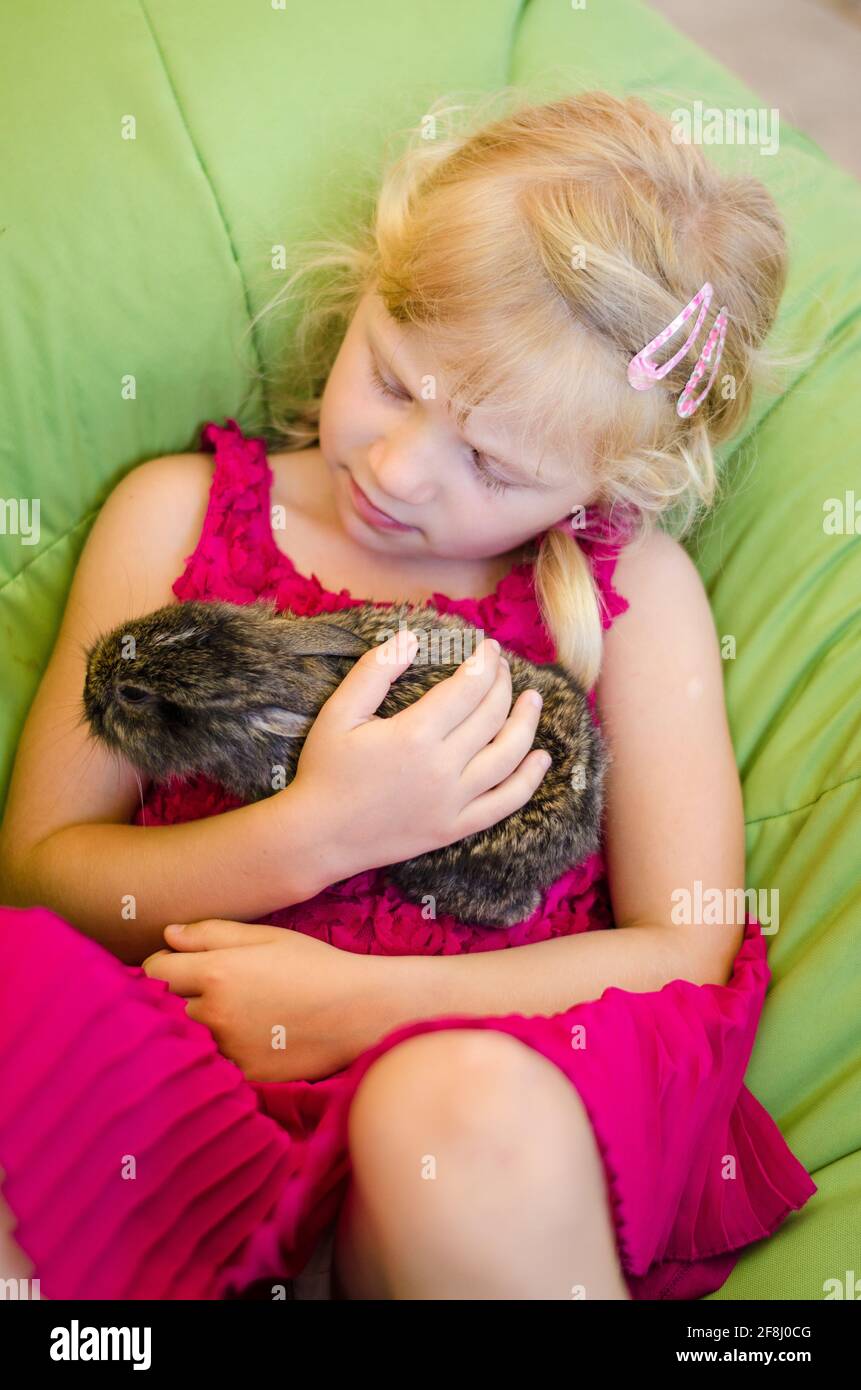 adorable petite fille blonde portant un lapin Banque D'Images