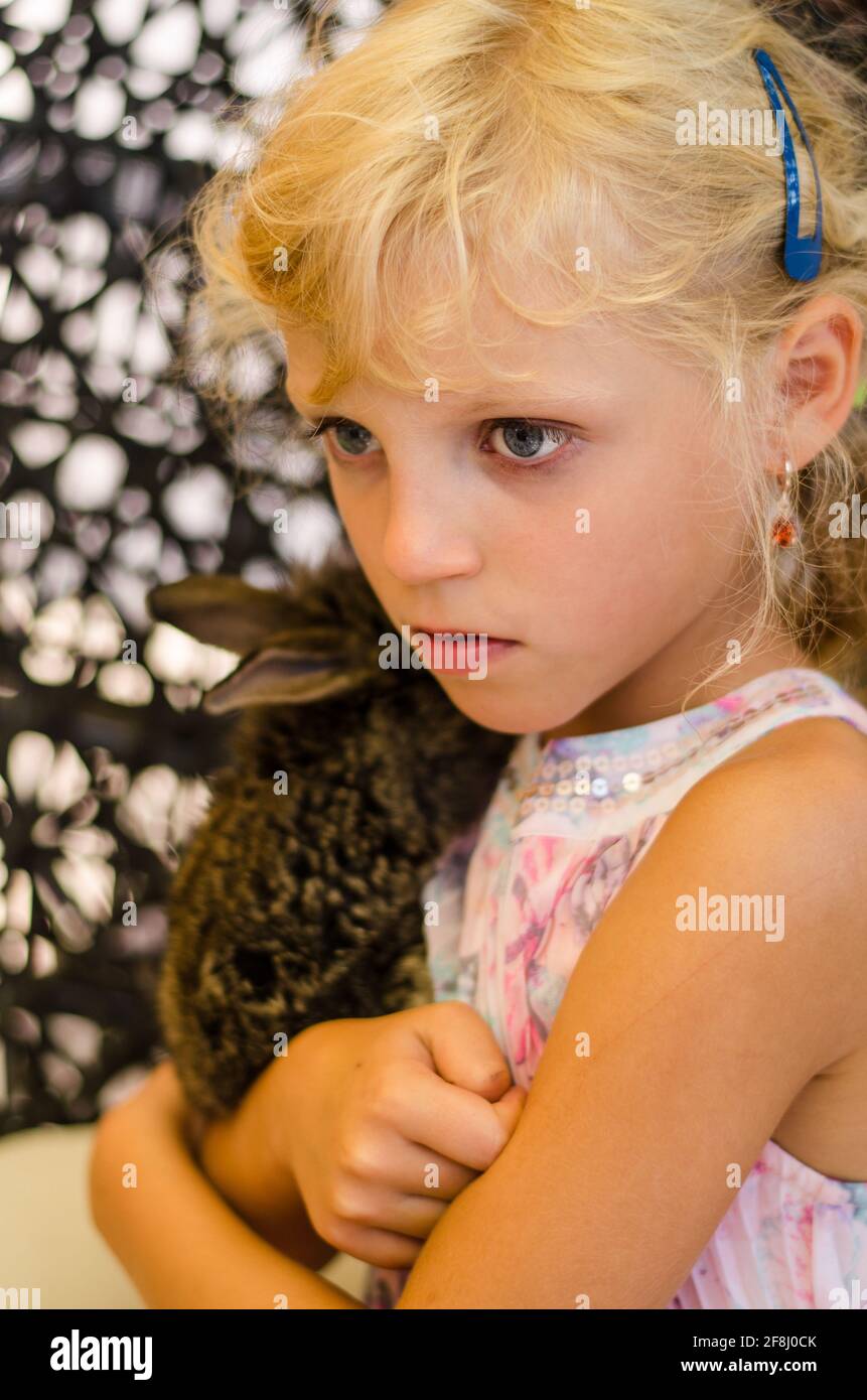 adorable petite fille blonde portant un lapin Banque D'Images