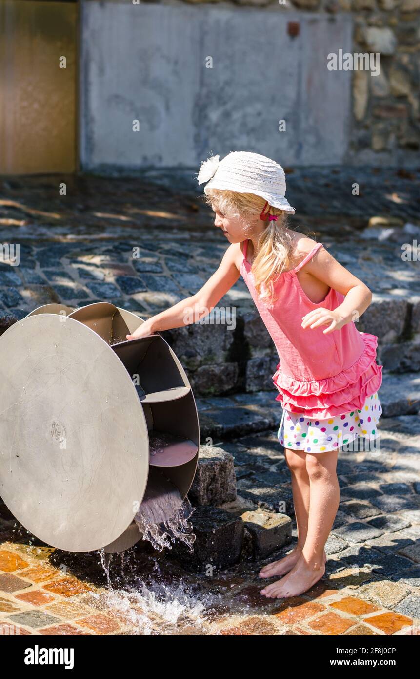 petite fille blonde jouant avec attraction de moulin à eau en bois Banque D'Images