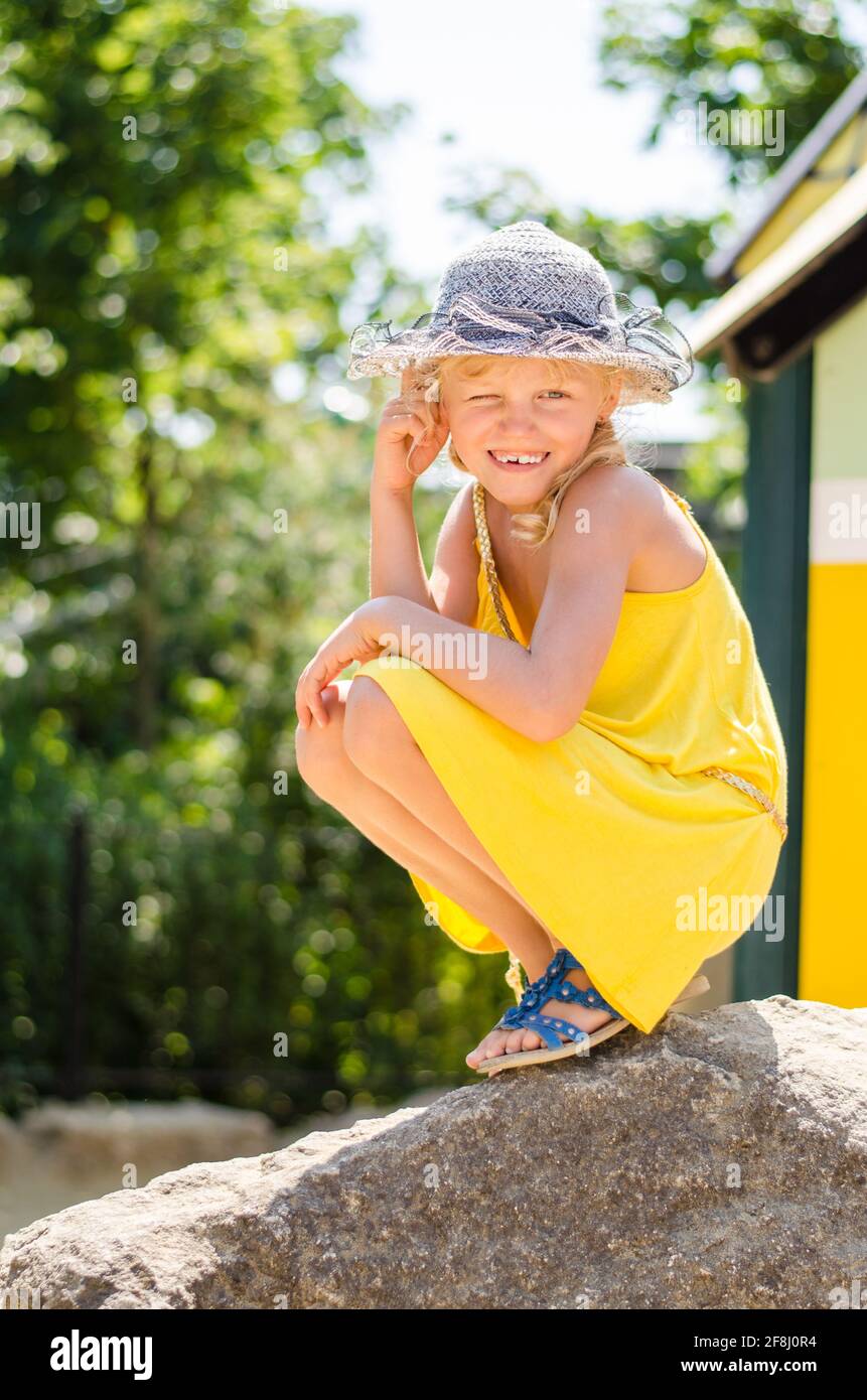 petite fille blonde en robe jaune jouant sur l'aire de jeux Banque D'Images