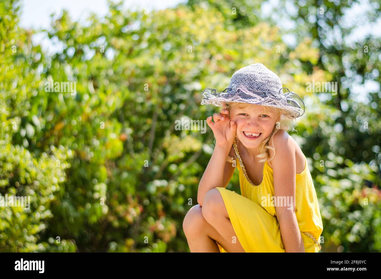 petite fille blonde en robe jaune assise Banque D'Images