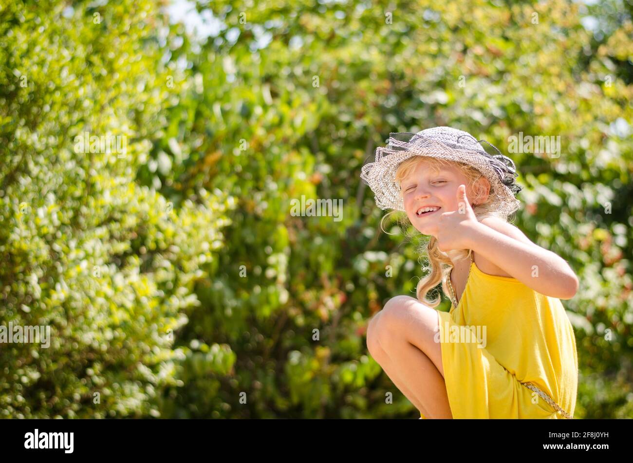 petite fille blonde en robe jaune montrant oui geste Banque D'Images