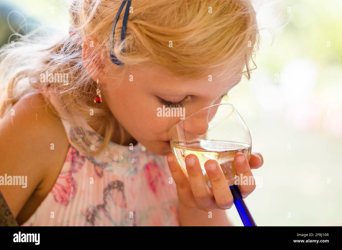 petite fille blonde boire du verre de fête Banque D'Images