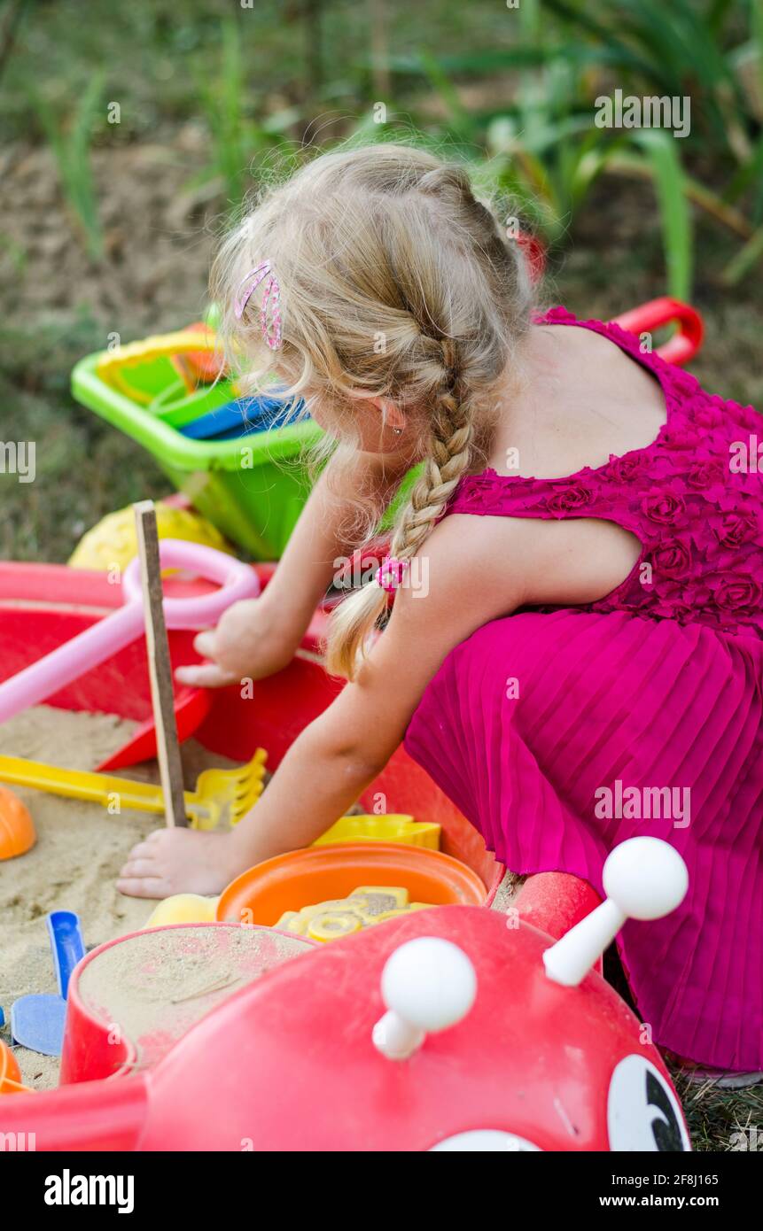 petite fille blonde jouant dans un bac à sable sur l'aire de jeux Banque D'Images