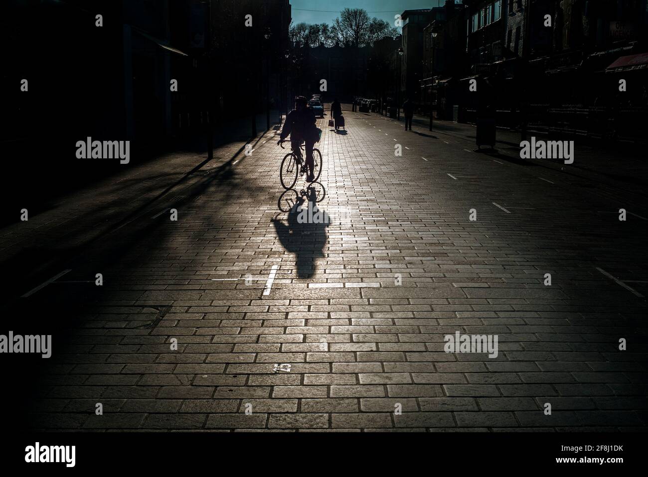 Silhouette d'homme méconnaissable à vélo, ombres sur une rue pavée, Inverness Street Camden, Londres UK Banque D'Images