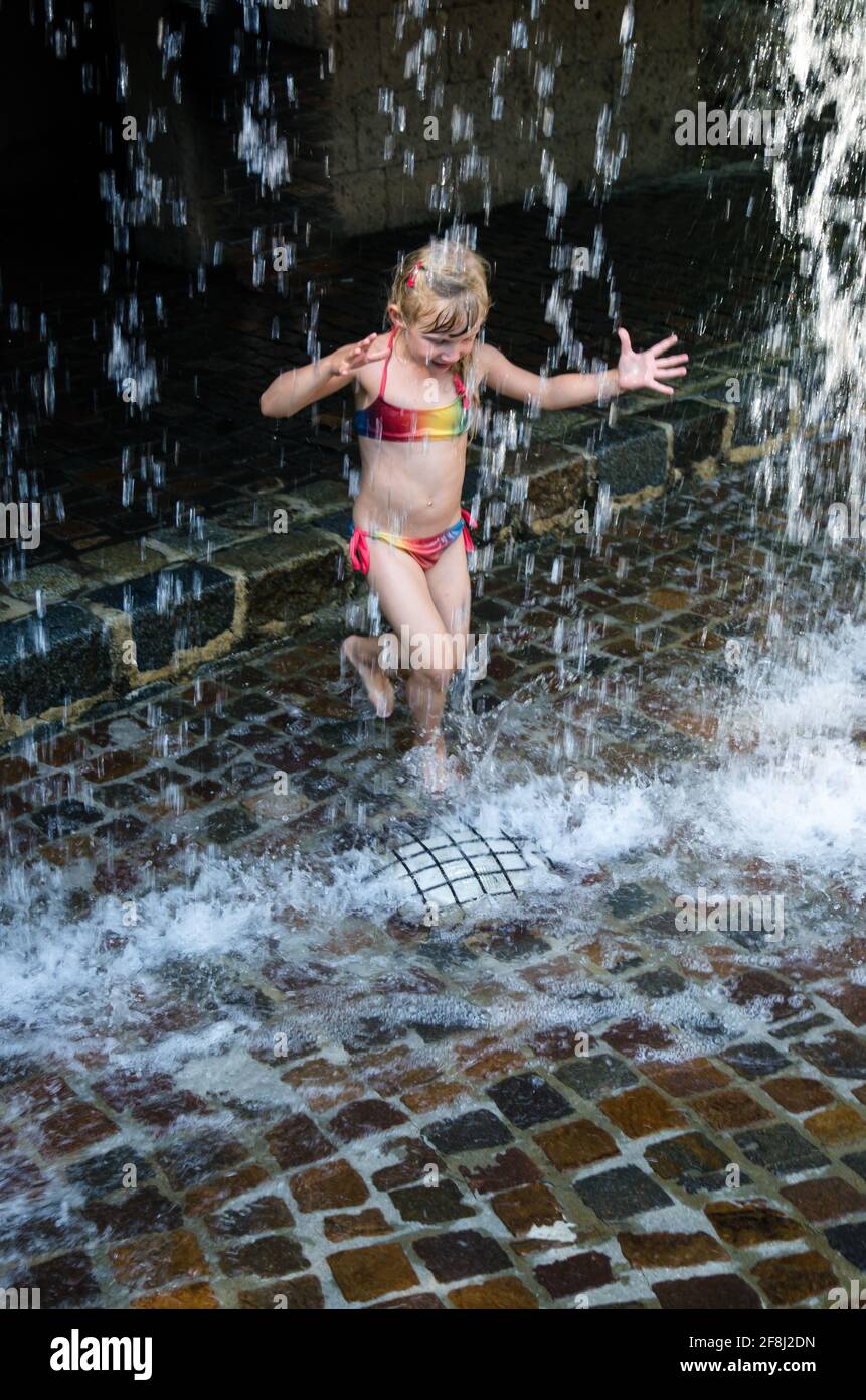 petite fille blonde jouant avec l'eau tombant Banque D'Images