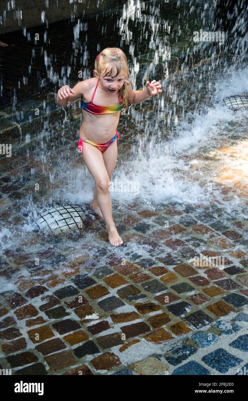 petite fille blonde jouant avec l'eau tombant Banque D'Images
