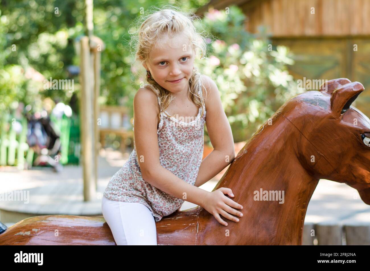 petite fille blonde à cheval en bois Banque D'Images