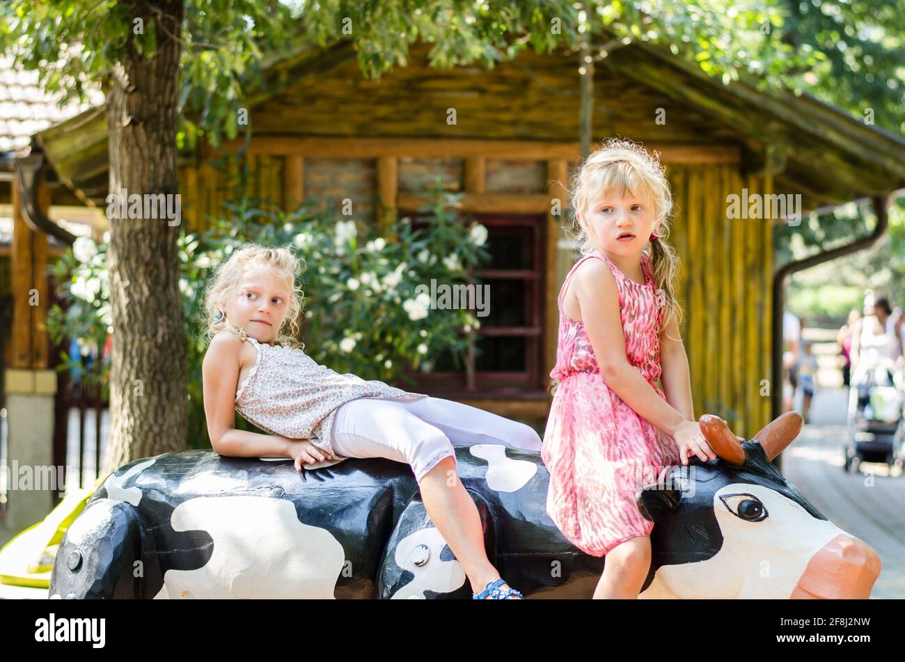petite fille blonde à cheval sur une vache en bois Banque D'Images