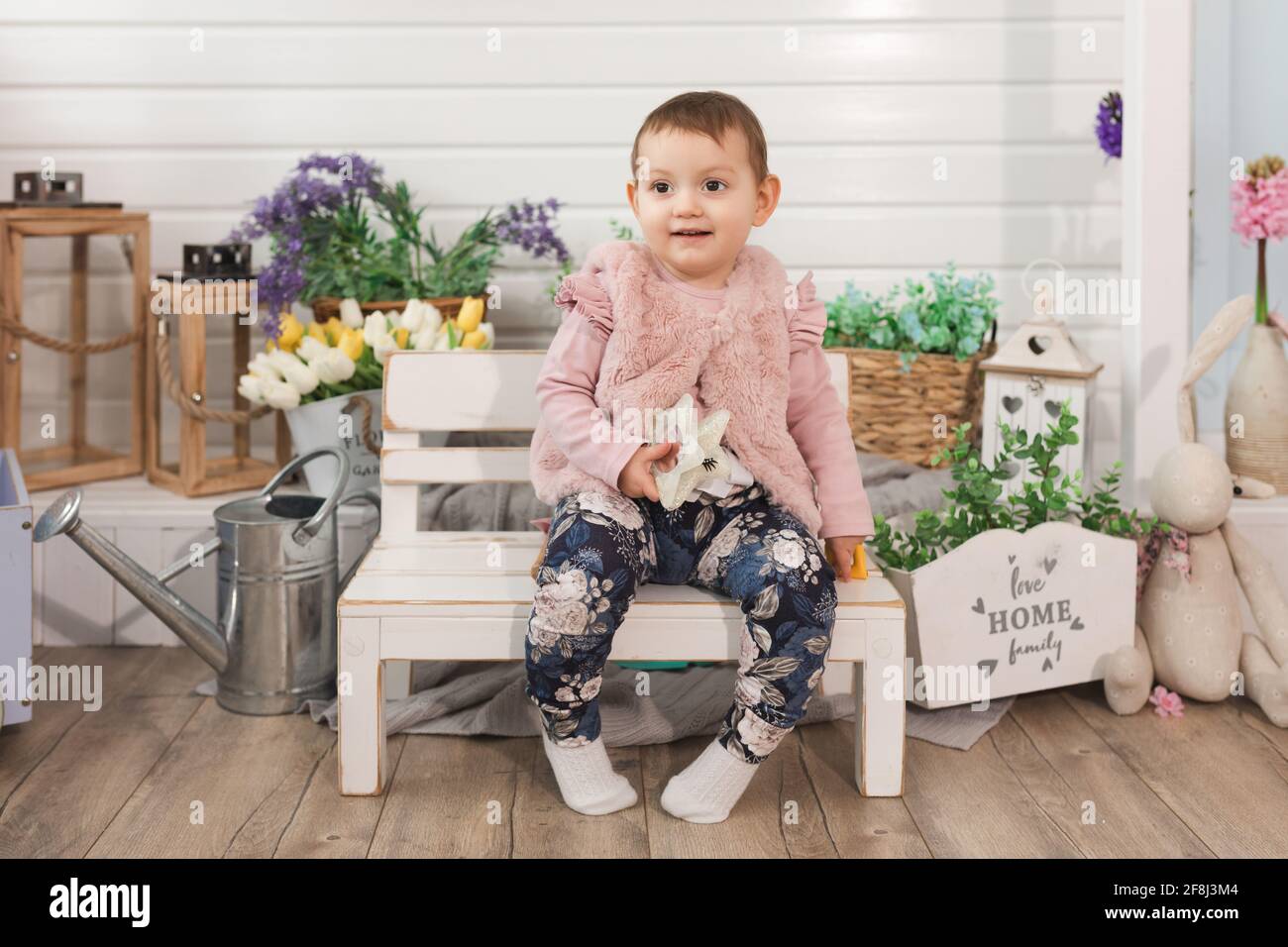 petite fille heureuse enfant d'un an assis sur un banc dans l'arrière-cour. sourit à l'extérieur. concept d'activités à temps libre pour les enfants Banque D'Images