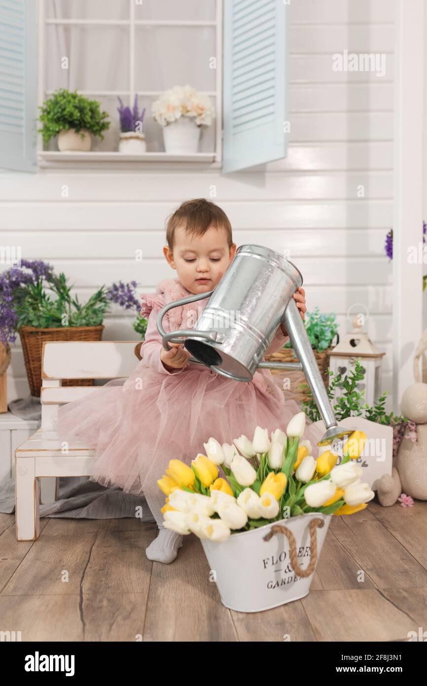 petite fille d'un an joue dans l'arrière-cour avec un métal arrosoir peut arroser des fleurs de tulipes. concept d'activités de temps libre pour les enfants Banque D'Images