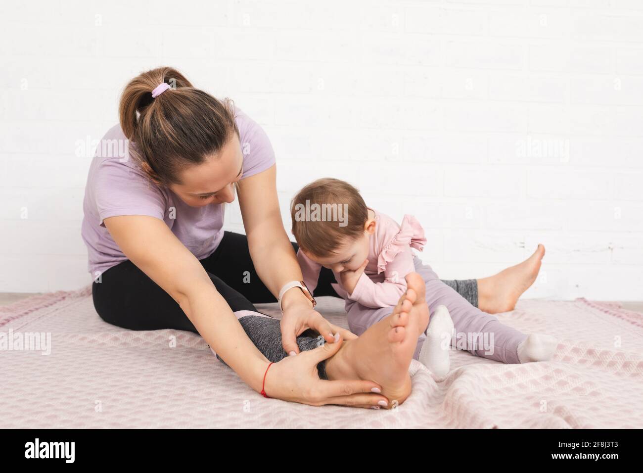 jeune mère gymnastique à la maison un enfant d'un an utilise un smartphone. temps libre ensemble concept de famille Banque D'Images
