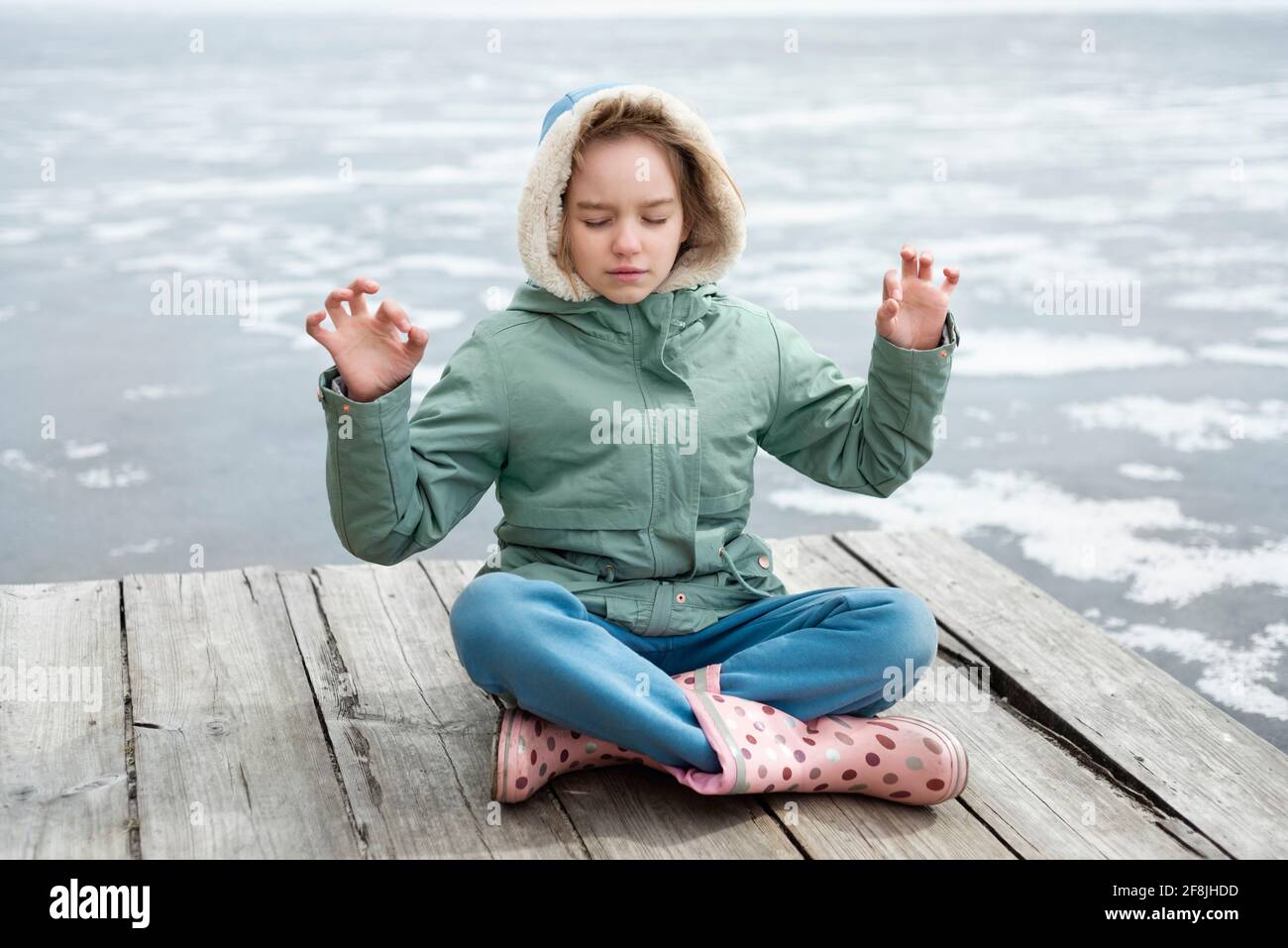 Jeune fille assise sur le pont près du lac et méditant Banque D'Images