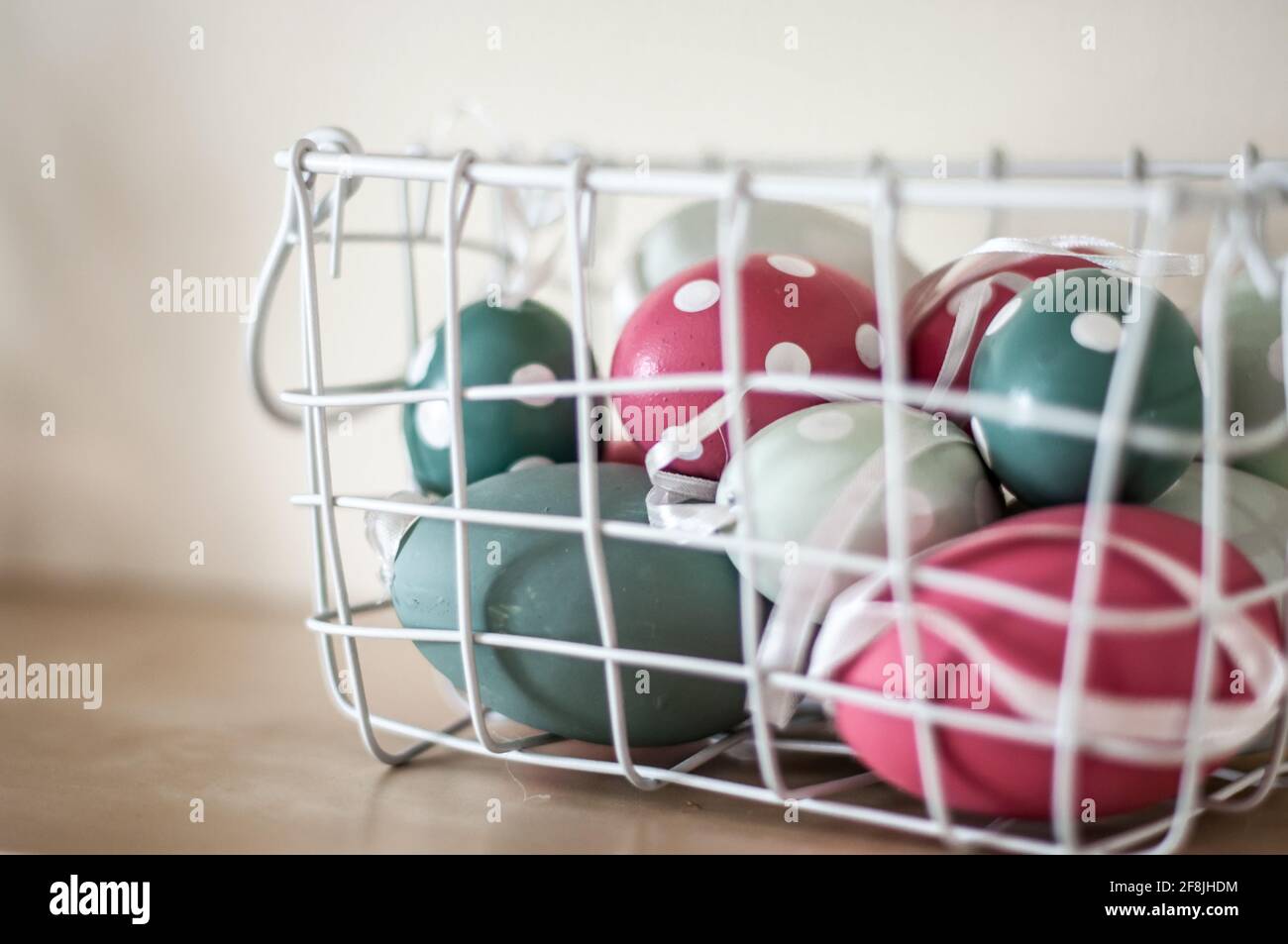 Oeufs de Pâques de couleur rose et verte de deux nuances dans un panier blanc. Banque D'Images