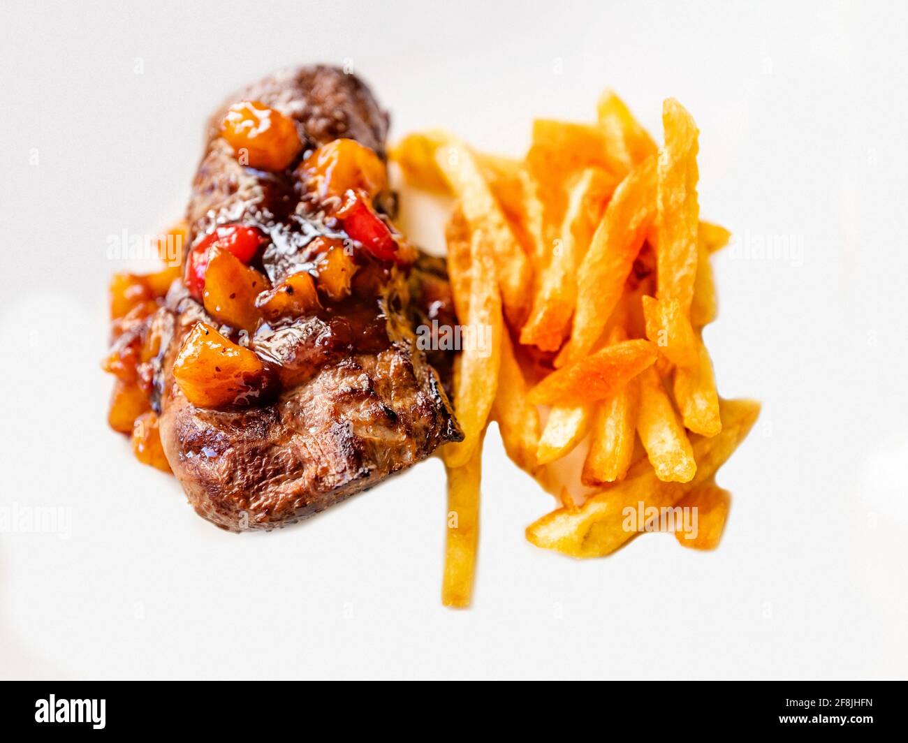 Steak de cerf avec morceaux de fruits et sauce sucrée, frites maison, isolé sur fond blanc, gros plan. Banque D'Images