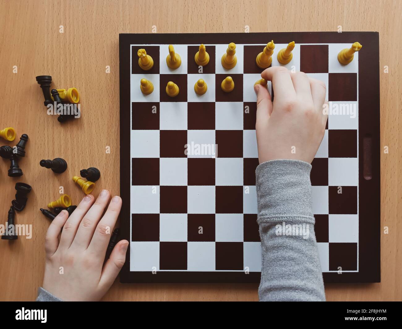 les mains des enfants organisent les échecs sur un échiquier vue de dessus de plus près Banque D'Images
