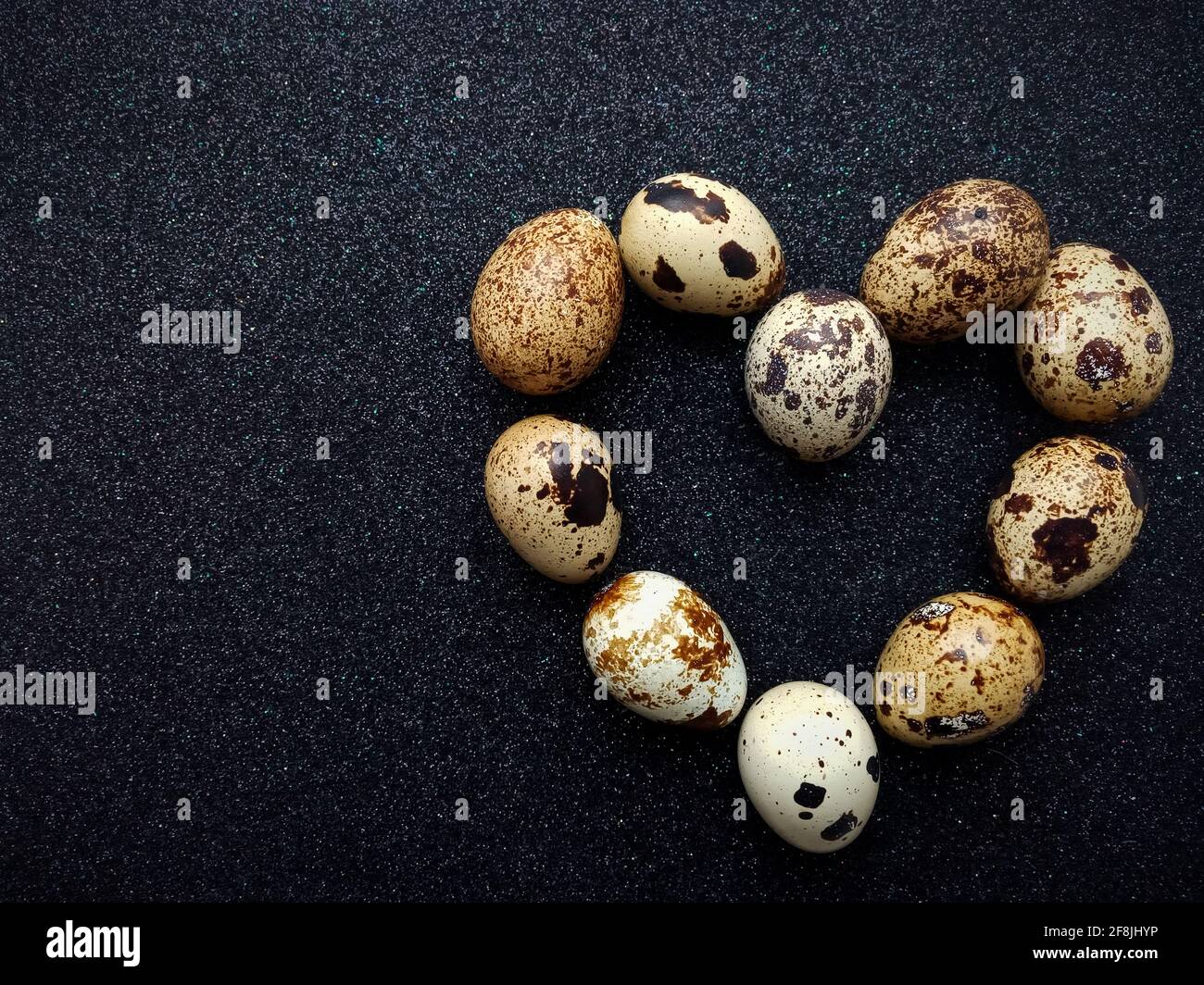 dix œufs de caille en forme de cœur un gros plan noir Banque D'Images