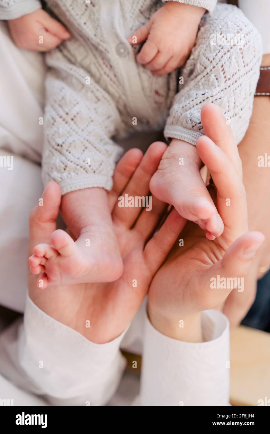 Gros plan des mains de la mère tenant les pieds de bébé. Banque D'Images