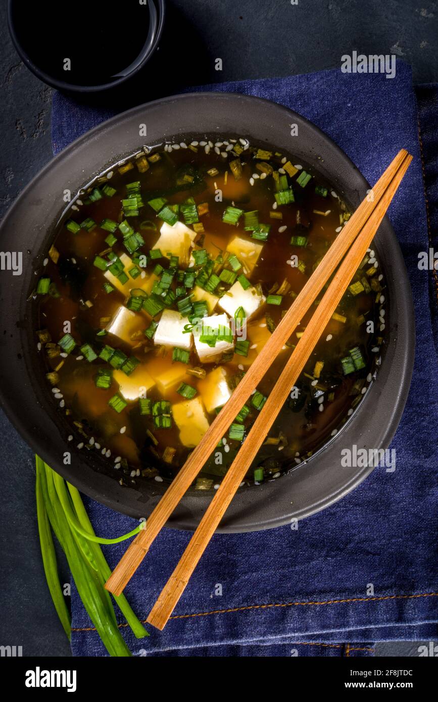 Soupe miso au bol en potelé, avec algues wakame, tofu et baguettes sur fond noir Banque D'Images