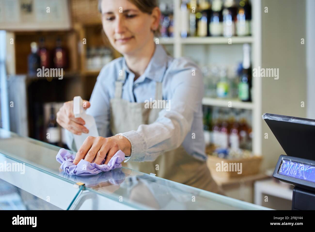 Femme propriétaire compteur de nettoyage Delicatessen avec vaporisateur aseptisant Banque D'Images