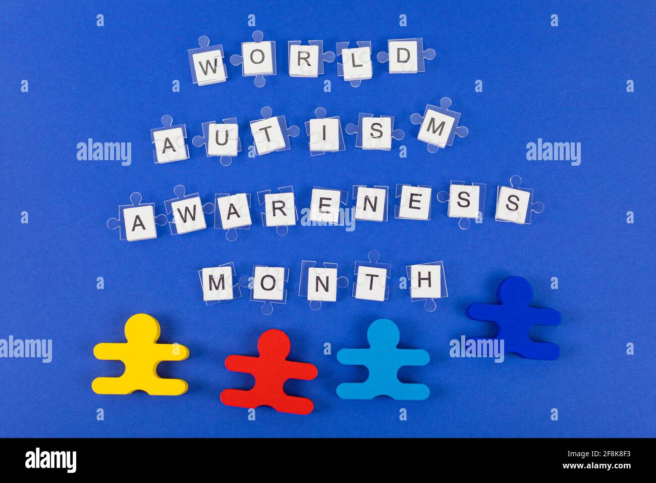 Mois mondial de sensibilisation à l'autisme. Détails transparents du puzzle sur l'inscription et quatre jouets en bois sur fond bleu. Banque D'Images