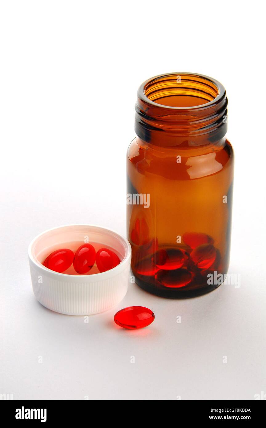 Comprimés de vitamine rouge en flacon sur fond gris Banque D'Images