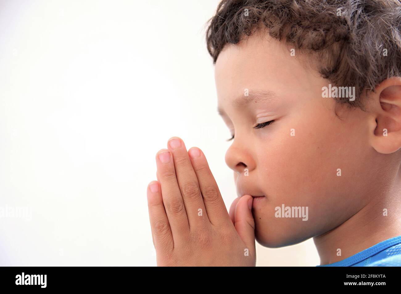 Garçon priant à Dieu avec les mains ensemble photo Banque D'Images