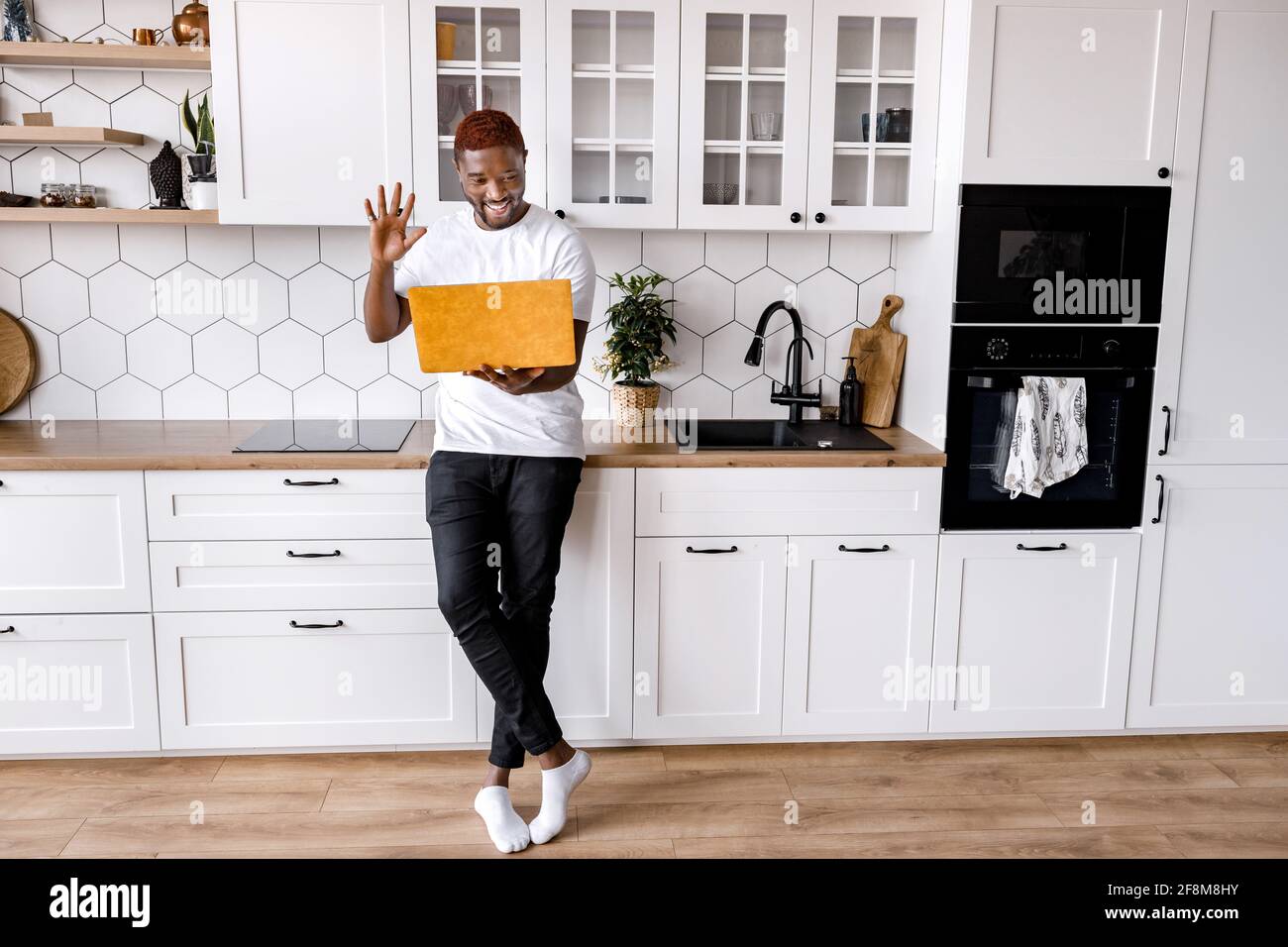 L'homme afro-américain utilise un ordinateur portable, il a une réunion vidéo avec des amis ou des collègues, leur saluant. Un homme joyeux, indépendant, est souriant Banque D'Images