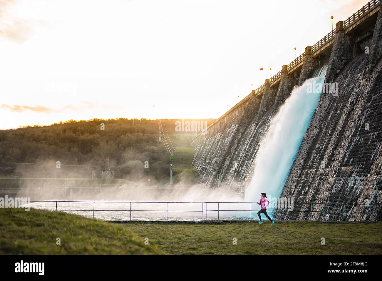 Espagne.Runner courant sur un barrage avec une cascade et la nature en arrière-plan.Sport style de vie. Banque D'Images