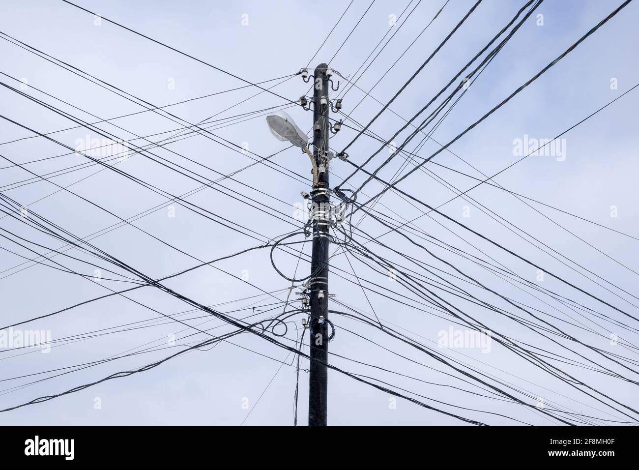 Land Line câbles électriques noirs désordonnés sur les poteaux électriques. Contre le ciel nuageux Banque D'Images