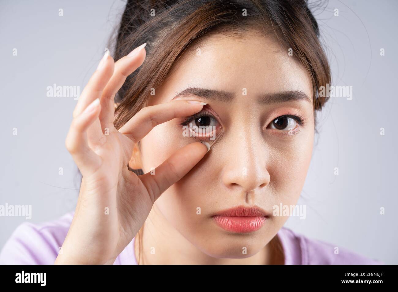 La jeune femme asiatique lui ouvrait les yeux main Banque D'Images