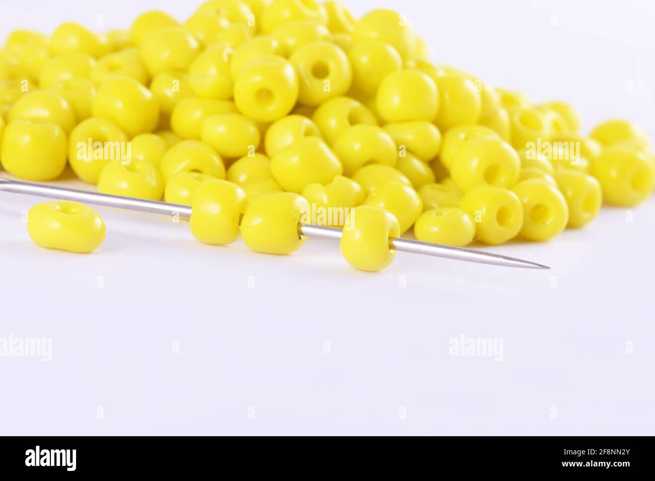 Perles étalées sur fond blanc avec aiguille perles avec aiguille gros plan, macro, faire collier de perles, perles crochet quotidien perles Banque D'Images