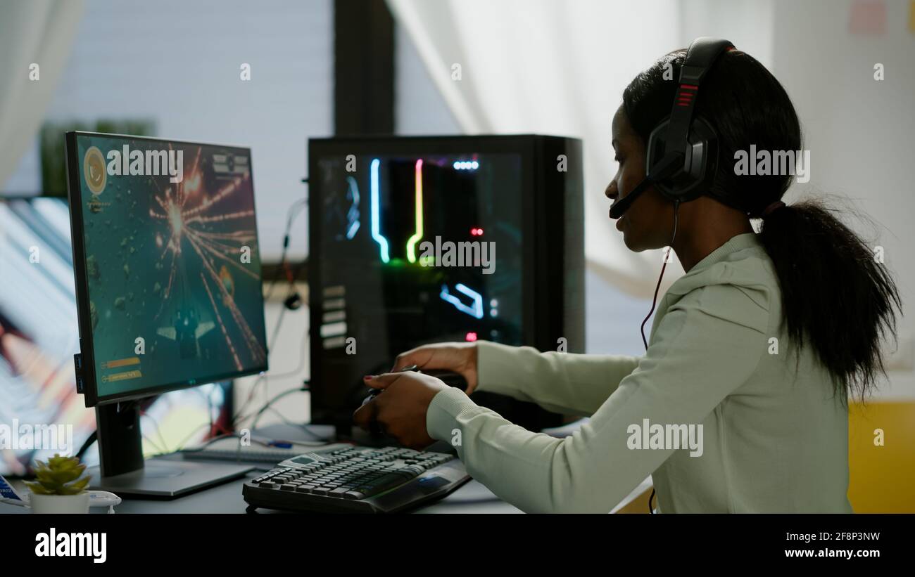 Used african Woman gamer streaming jeux vidéo en ligne et perdre jouer sur RGB puissant ordinateur à l'aide de la commande sans fil. Joueur avec un casque célébrant la victoire dans la salle de jeux Banque D'Images