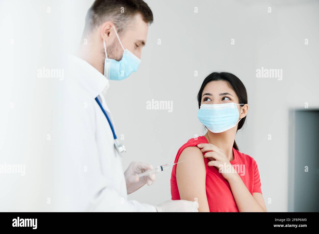 un médecin de sexe masculin sur un manteau blanc est détenteur d'un coronavirus vaccin dans ses mains à côté d'un patient Banque D'Images