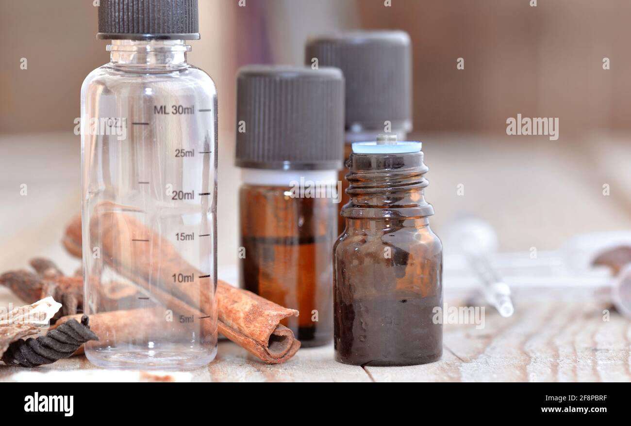 bouteilles d'huile essentielle et bouteille vide graduée avec épices sur une table en bois Banque D'Images