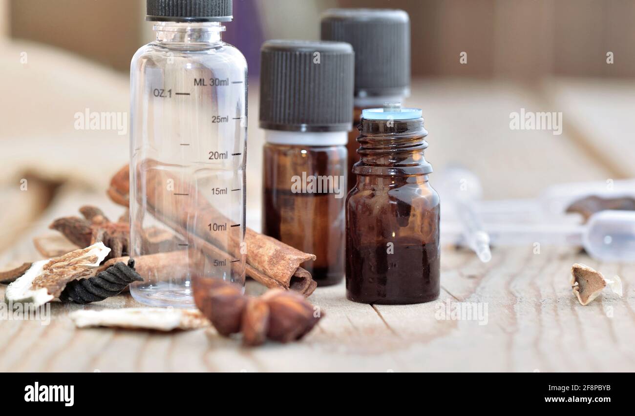bouteilles d'huile essentielle et bouteille vide graduée avec épices sur une table en bois Banque D'Images